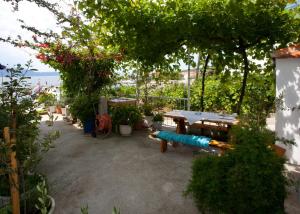 eine Terrasse mit einem Tisch, einer Bank und Bäumen in der Unterkunft Apartments Toplak in Sućuraj