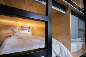 a bedroom with a bunk bed with white sheets at GiG Capsule Hostel in Ericeira