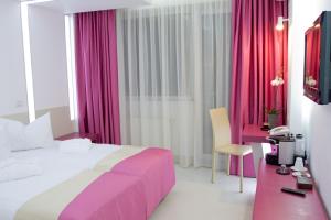 ブカレストにあるクリスティーナ ホテルの大きなベッドとピンクのカーテンが備わるホテルルームです。