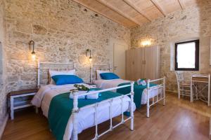 a bedroom with two beds and a stone wall at Trigono Kaliviani, 4BDR - 3BR - 8 people in Kissamos
