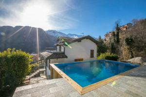 a swimming pool in front of a house with mountains at Casa dei Galli in Gravedona