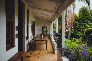 Cypress Cottage Guest House في سويلندام: شرفة منزل مع طاولة وكراسي