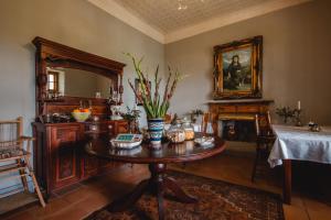 a living room with a table and a fireplace at Cypress Cottage Guest House in Swellendam