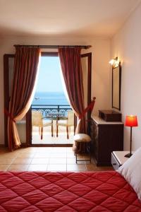 a bedroom with a large window with a view of the ocean at Kekrifalia Hotel in Skala