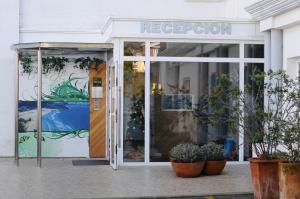 un frente de tienda con un cartel en la puerta y plantas en Apartamentos Turisticos Noray, en Argoños