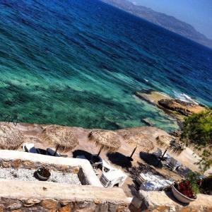 a beach with chairs and umbrellas and the ocean at Kekrifalia Hotel in Skala