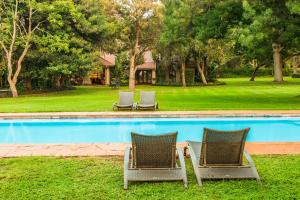 duas cadeiras de jardim sentadas ao lado de uma piscina em Sondela Nature Reserve & Spa Country House em Bela-Bela