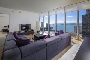 sala de estar con sofá grande con almohadas moradas en Miami Icon Brickel Luxury Condo, en Miami