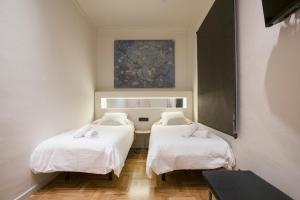 バルセロナにあるTendency Sagrada Familia Luxuryの白いシーツと絵画が備わるベッド2台付きの部屋