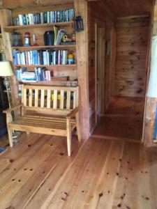 a room with a bench and book shelves with books at Camp Mitigwa Rental in Rangeley