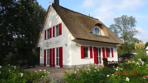 una pequeña casa blanca con persianas rojas en Ferienhaus Lucia, en Glowe