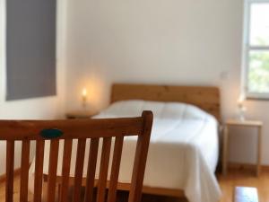 a bedroom with a bed and a wooden chair at Casa d'Avó Francisco in Madalena