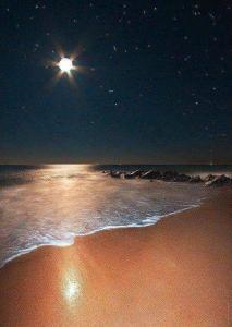 a beach at night with the moon and the ocean at Issablanca in Oualidia