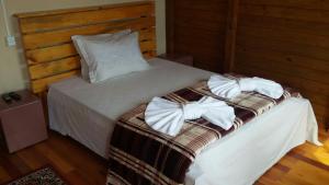 a bed with white towels on top of it at Pousada e Restaurante Redivo in Louro Müller