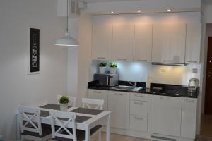 una cocina con armarios blancos y una mesa con sillas. en Apartament Aleksandra, en Świnoujście
