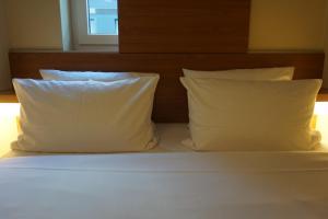 a bed with a white comforter and pillows at easyHotel Berlin Hackescher Markt in Berlin