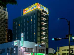 a tall building with a neon sign on top of it at Super Hotel Yonago Ekimae in Yonago