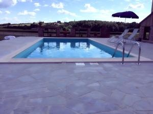 a swimming pool with two chairs and an umbrella at Apartments Mali Raj in Dolenci