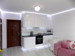 a small kitchen with white cabinets and a pink couch at Apartment Silvi in Varna City