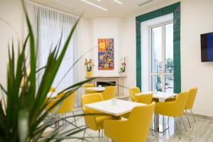 a dining room with yellow chairs and tables and a fireplace at The Five Rooms Napoli in Naples