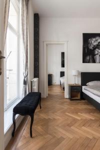 a bedroom with a wooden floor and a bed and a bench at Roaring 20's Apartment Meir in Antwerp