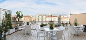 un patio con mesas blancas y sillas en la azotea en The Five Rooms Napoli, en Nápoles
