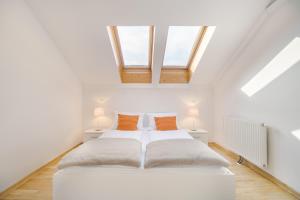 a white bedroom with two beds and two windows at Apartment Fine Dalmatinova in Ljubljana