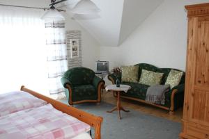 a bedroom with a couch and two chairs and a tv at Ferienwohnung Kredig in Poppenhausen