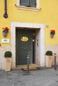 a green door on a yellow building with two plants at Relais Ponte Pietra in Verona