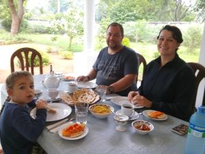 two adults and a child sitting at a table with food at First House Mihintale in Mihintale