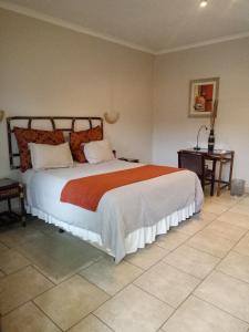 ein Schlafzimmer mit einem großen Bett mit einer orangefarbenen Decke in der Unterkunft Planet Hotel HollyBum in Lubumbashi