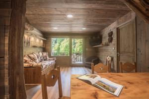 a living room with a couch and a table with a book at Le Couarôge Chalets et Appartements in La Bresse