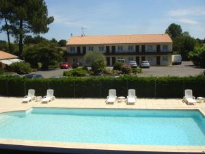 a swimming pool with lounge chairs and a building at Hôtel Restaurant Les Bruyères in Saint-Médard-en-Jalles