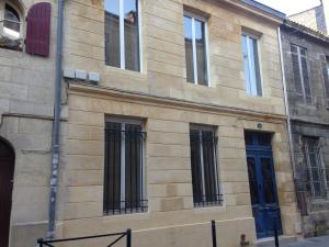 - un bâtiment en pierre avec des fenêtres noires et des portes bleues dans l'établissement Les Chambres d'Art, à Bordeaux