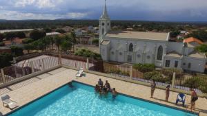 a group of people standing in a swimming pool in front of a church at Hotel Cariris in Pirapora