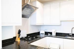 a kitchen with white cabinets and a stove top oven at Access Little Venice in London