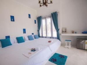 a bedroom with a large white bed with blue pillows at Laemsing Whitehouse Resort in Laem Sing