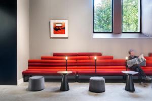 a man sitting on a red couch in a room at One Shot Tabakalera House in Donostia-San Sebastián
