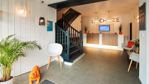 a lobby with a staircase and a white chair at Logis Hôtel La Chaize in Noirmoutier-en-l'lle