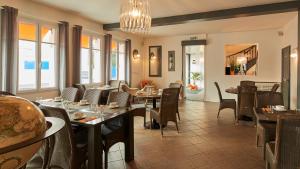 a restaurant with tables and chairs and a chandelier at Logis Hôtel La Chaize in Noirmoutier-en-l'lle