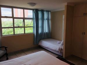 a bedroom with a window and a bed and a window at Strandburg Holiday Apartments in Amanzimtoti