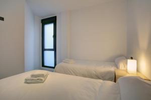een witte kamer met 2 bedden en een raam bij Lewis&Peter Apartments Los Remedios in Ronda