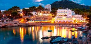 a group of buildings on the shore of a river at night at Granada Apartments Familiar Deluxe in Portinatx