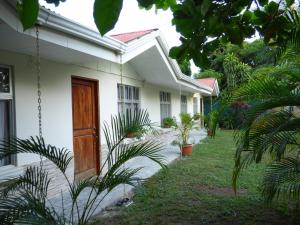 ein weißes Haus mit einer Holztür im Hof in der Unterkunft Tropical Housing by El Rodeo - Calle El Manglar in Puerto Jiménez