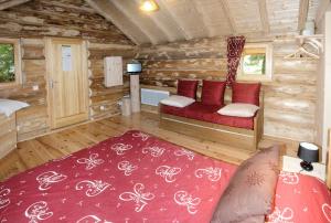 une cabane en rondins avec un canapé rouge dans une chambre dans l'établissement Chambres d'hôtes La Gargaille, à Alièze