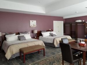 2 camas en una habitación con mesa y escritorio en Riverview B&B, en Gananoque