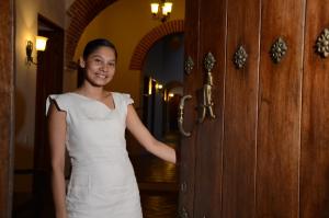 Una donna con un vestito bianco in piedi accanto a una porta di Alfiz Hotel a Cartagena de Indias