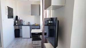 eine kleine Küche mit einem schwarzen Kühlschrank und einem Tisch in der Unterkunft La plus belle de main in Marseille