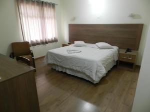a bedroom with a large bed with a wooden headboard at Príncipe Hotel in Poços de Caldas