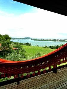 un balcón con hamaca y vistas al agua en Pousada Águas de Ibiraquera Suite Master, en Imbituba